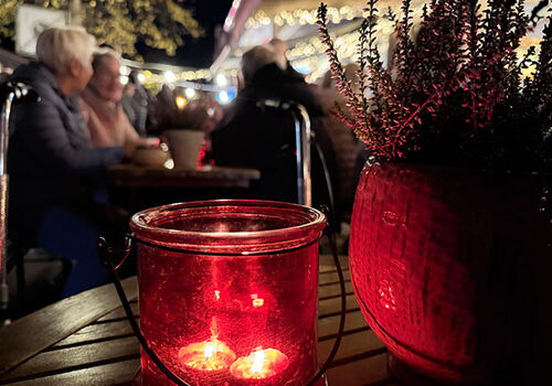 Kerze und Pflanze auf Tisch im Freien bei Nacht.