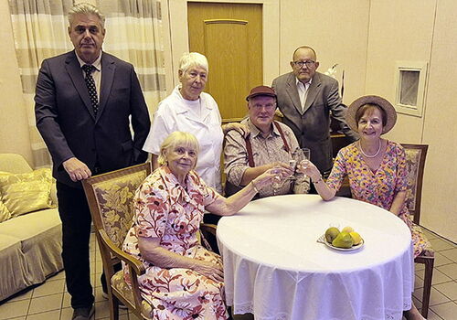 Gruppe von sechs Menschen an einem Tisch mit Obst.