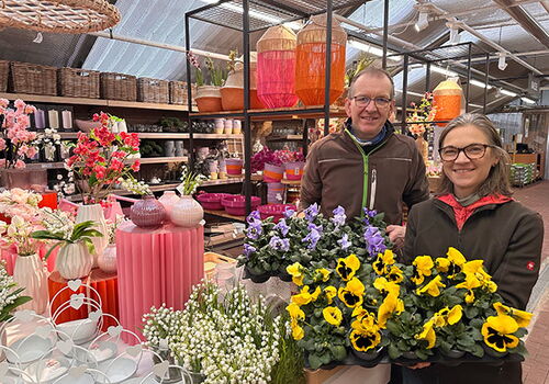 Zwei Personen halten Blumen im Gartencenter.