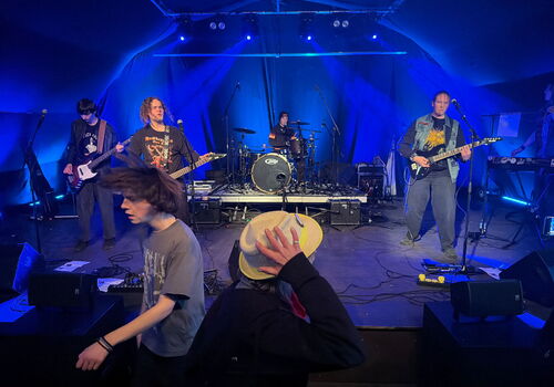 Band spielt live auf der Bühne mit blauem Licht.