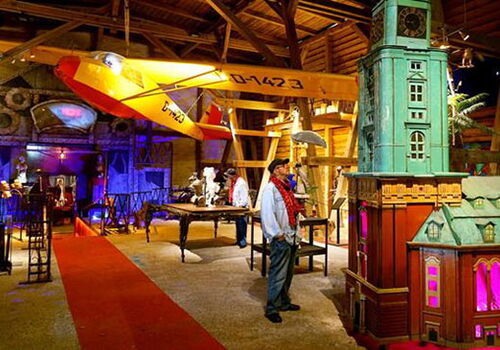 Innenraum mit Flugzeug, Turm und Besucher in einer Ausstellung.