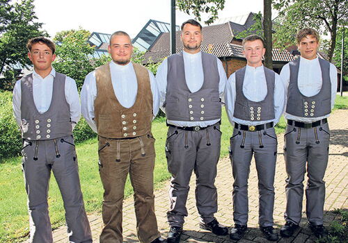 Fünf Männer in traditioneller Kleidung im Freien.
