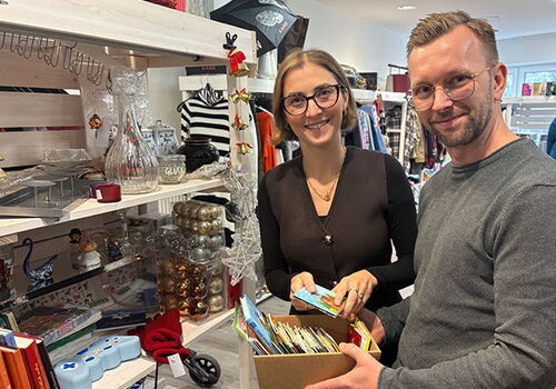 Zwei Menschen mit Kartenbox in einem Dekoladen.