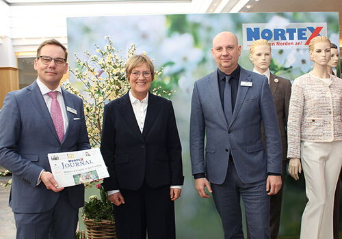 Drei Personen posieren vor einem Nordtex-Hintergrund.