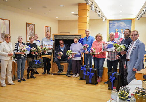 Gruppe von Personen hält Blumensträuße und Urkunden.
