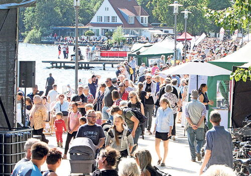 Menschenmenge bei einem Outdoor-Event an einem See.