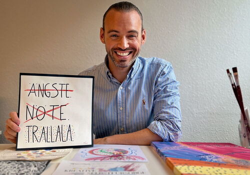 Mann am Tisch mit Schild: Ängste, Nöte, Trallala.