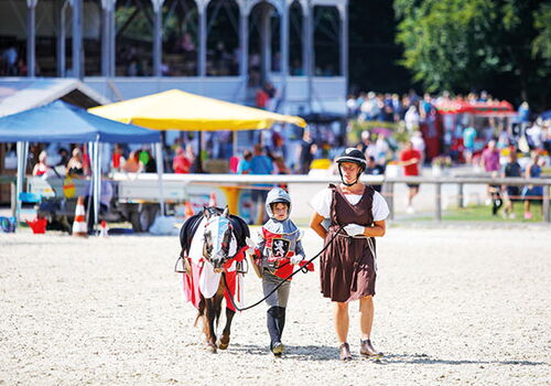 Zwei Personen führen ein Pony auf einer Veranstaltung.