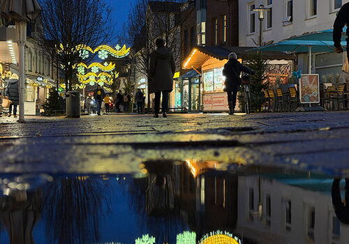 Lichterdekoration in der Straße mit Spiegelung in einer Pfütze.