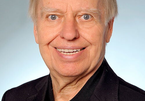 Ein lächelnder älterer Mann in schwarzem Anzug