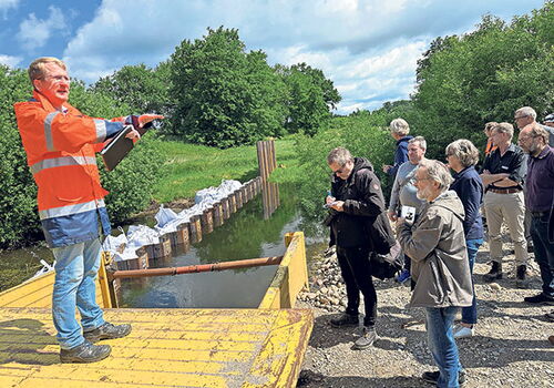 Mann erklärt Gruppe ein Projekt an einem Fluss