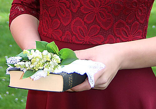 Frau hält ein Buch mit Blumenstrauß in der Hand.