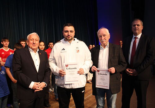 Männer stehen auf einer Bühne mit Urkunden