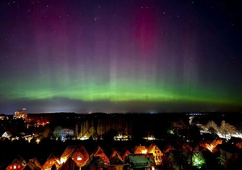 Nordlichter über einer Stadt bei Nacht