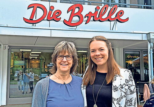 Zwei Frauen lächeln vor einem Geschäft namens Die Brille.