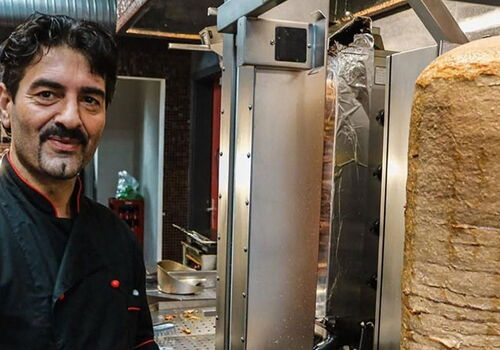 Mann bereitet Döner Kebab an der Theke zu.