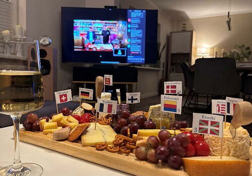 Käseplatte und Wein vor einem Fernseher im Wohnzimmer.