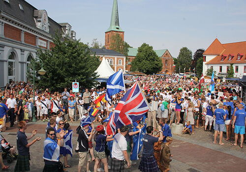 Menschenmenge mit Flaggen auf einem Stadtplatz
