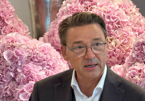 Mann mit Brille vor rosa Hortensienblüten