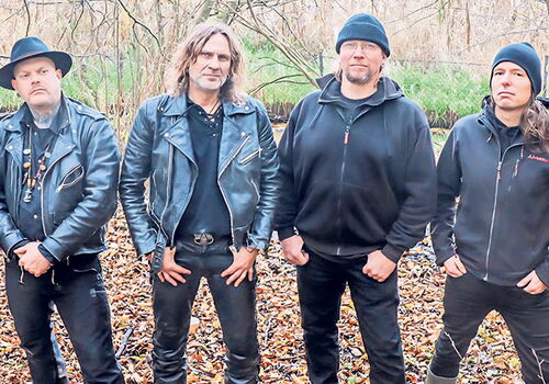 Vier Männer in Lederjacken stehen im Herbstwald.