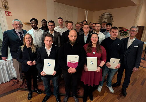 Gruppe von Menschen mit Urkunden posiert bei Veranstaltung.