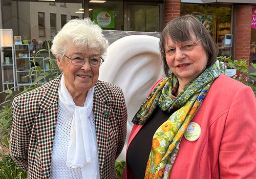 Zwei Frauen lächeln vor einem Geschäft.