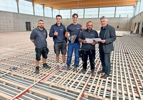 Team auf Baustelle mit Holzbodenaufbau und Plänen