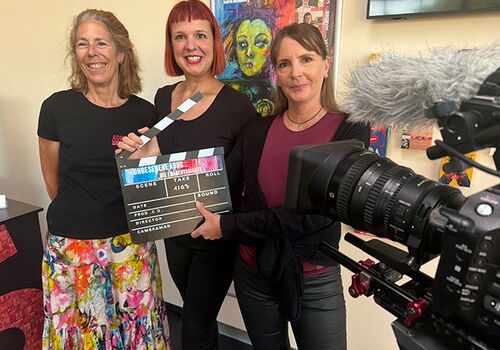 Drei Frauen posieren mit Filmausrüstung in einem Raum.