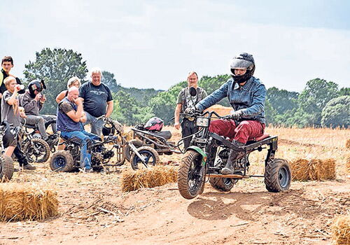Person fährt selbstgebautes Trike auf Feldweg.