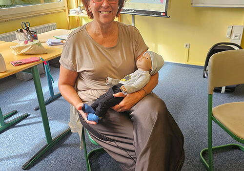 Frau hält Puppe in einem Klassenzimmer mit Frankreichkarte.