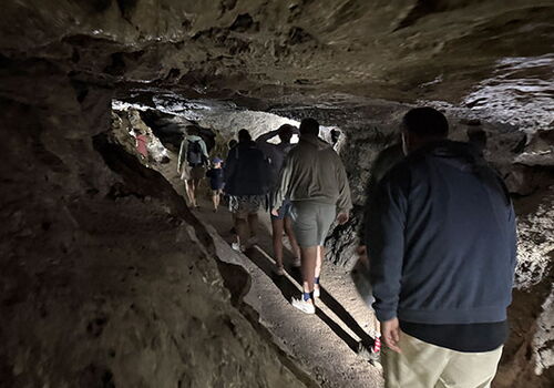 Gruppe von Menschen erkundet eine enge, natürliche Höhle.