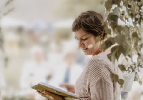 Frau liest im Freien aus einem Buch vor.