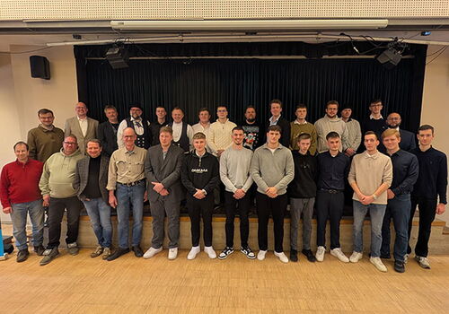 Gruppe von Menschen posiert auf einer Bühne in einem Raum.