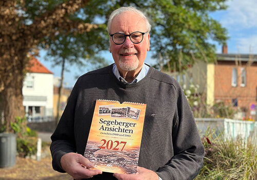 Mann mit Kalender 'Segeberger Ansichten 2027' in der Hand.