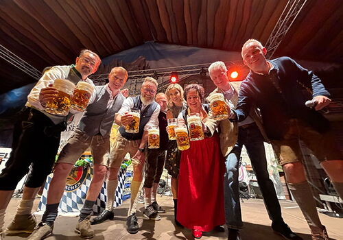 Gruppe in Tracht mit Bierkrügen auf der Bühne.