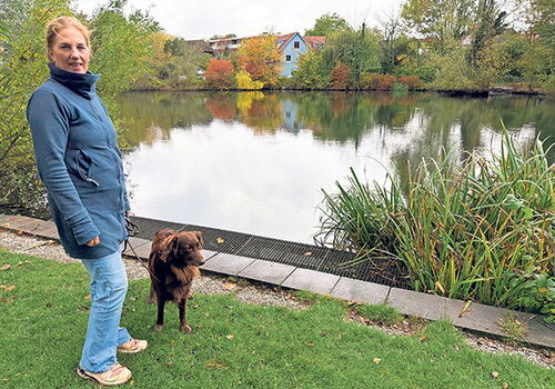 Frau mit Hund spaziert am See im Herbst.