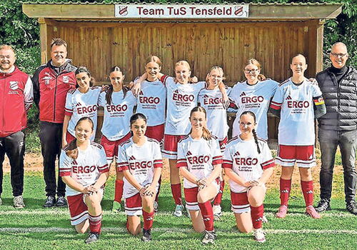 Fußballfrauenmannschaft mit Trainern auf dem Spielfeld.