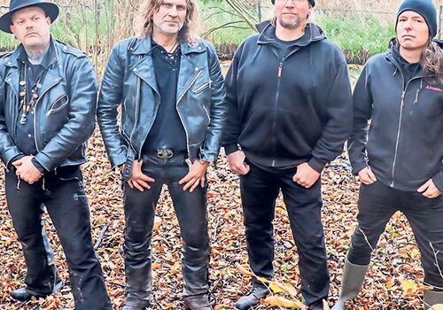 Vier Männer in Lederjacken stehen im Herbstwald.