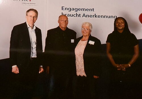 Vier Personen vor einem Plakat bei einem Event.
