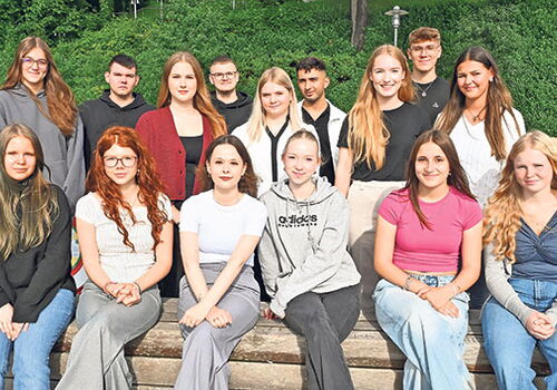 Gruppe von jungen Menschen auf einer Holztreppe im Freien.
