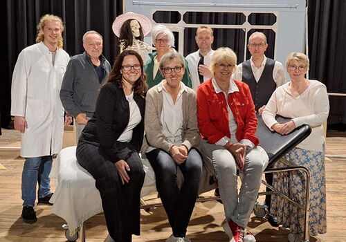 Theatergruppe auf einer Bühne mit Requisiten.