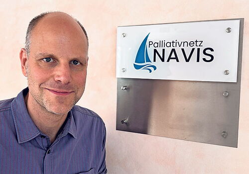 Mann neben Palliativnetz NAVIS Schild