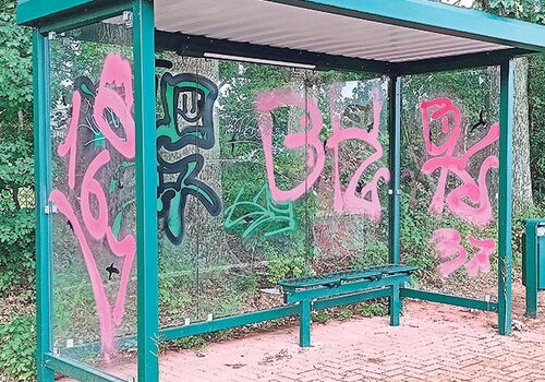 Bushaltestelle mit Graffiti auf Glaswänden.