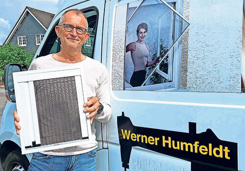 Mann hält Insektenschutzrahmen vor Lieferwagen.