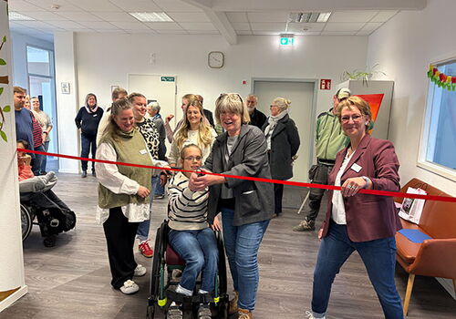 Personen schneiden ein rotes Band in einem Büro durch.