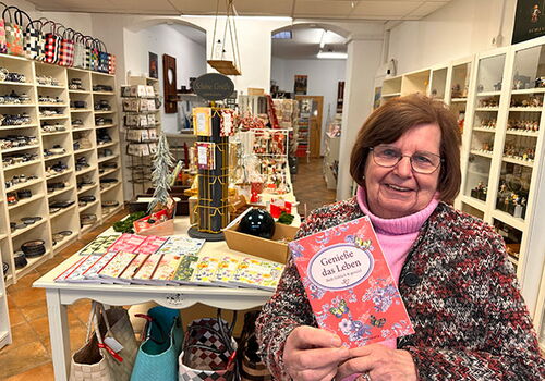 Frau im Laden mit einer Karte: Genieße das Leben.