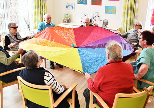 Senioren spielen mit einem bunten Schwungtuch im Kreis