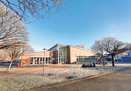 Modernes Gebäude mit Bäumen und blauem Himmel.