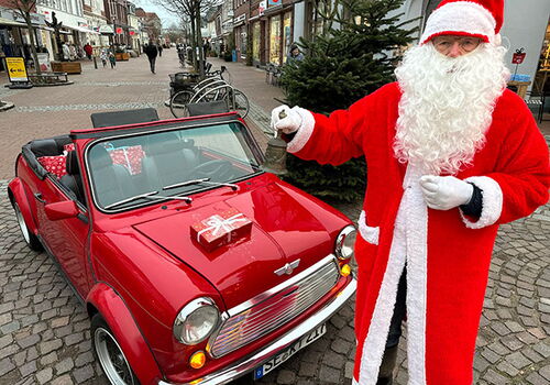 Weihnachtsmann mit rotem Auto voller Geschenke