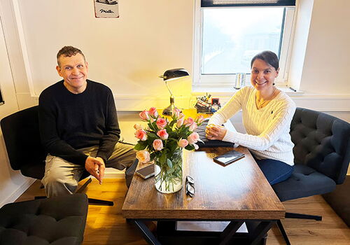 Zwei Leute am Tisch mit Blumen und Lächeln.